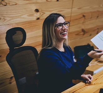 Smiling dental receptionist takes paperwork from client