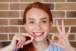 Woman holding her extracted tooth and smiling